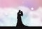 Silhouette of a bride and groom on a pastel cotton candy clouds background