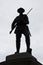 Silhouette of a bronze British Tommy statue with drawn bayonet on a UK war memorial