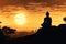 Silhouette of Buddha on golden sunset background.