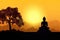 Silhouette of Buddha on golden sunset background.