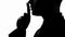 Silhouette of businessman showing silence gesture to someone, secrets and gossip