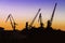 Silhouette of of cargo cranes. Port wharf landscape. Bright sunset, bright sky. Evening in the port