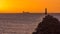 Silhouette of cargo ship at golden hour with lighthouse on Bull Island