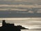 Silhouette of the castle of Lerici at sunset. Sky with clouds and sea of gold color