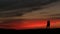 Silhouette of the charming couple gently kissing over the beautiful red and grey sky during the sunset.