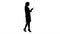 Silhouette Cheerful cute young woman doctor typing text on phone while walking.