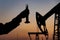 Silhouette of a chemical engineer taking a sample of crude oil against the background of oil pumps