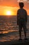 Silhouette of a Child in Front of Sea at Sunset