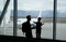 Silhouette of child and his father looking at plane through the window of airport terminal. Family journey lifestyle