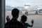 Silhouette of child and his father looking at preparation airplane through the window of airport terminal. Family journey