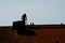 Silhouette of a chimney sweeper on top of a roof