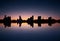 the silhouette of city buildings in the middle of a lake at dusk