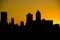 Silhouette of city skyline against orange setting sun