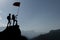 Silhouette climbers with flag on mountain