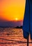 Silhouette of a closed beach blue umbrella on a background of sea sunset