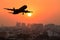 Silhouette commercial plane flying over city during sunset