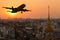 Silhouette commercial plane flying over city during sunset