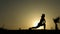 Silhouette of concentrated girl performing yoga poses, meditating against sunset