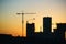 Silhouette of construction cranes over new residential buildings at sunset. Urban background