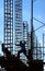 Silhouette of construction worker jumping across scaffolding among steel framing