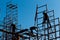 Silhouette of construction workers against sky on scaffolding wi