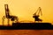 Silhouette of container crane at Osaka port are loading on evening with sunset color tone and gantry crane working background