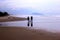 Silhouette of a couple and a dog walking on the beach in the morning