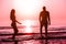 Silhouette of couple having fun inside ocean at sunset - Lovers having tender moments summer vacation - Holidays, relationship and