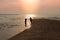 Silhouette of the couple held hands together at the seashore.