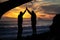 Silhouette of a couple high fiving at the beach during a beautiful sunset. Olympic National Park, Washington.