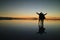 Silhouette of a couple raising their arms for the happy moment on the incredible mirror effect of Uyuni Salt Flats, Bolivia