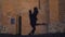 Silhouette of a couple in the shadow actively dancing on a stone wall.
