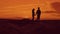 Silhouette of couple walking on beach at sunset holding hands. happy man and girl on seashore in the lights of sunset