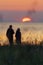 Silhouette of couple walking by the coast and watching the setting sun