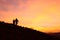 Silhouette of a couple of young female hikers watching the sunrise amidst a beautiful warm toned cloudscape at the top of a grassy