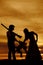 Silhouette of cowboy couple hold saddle and gun