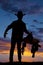 Silhouette of cowboy holding saddle at hip hand out