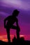 Silhouette of a cowboy stand with foot on saddle hand on knee