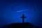 Silhouette of crucifix cross on mountain at night time with star and space background.