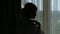 Silhouette of a cute girl in a negligee near the window. Shadow.