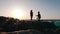 Silhouette of cute man standing on his knee and making proposal his girlfriend at sunset. Young amazed happy woman agreeing to mar