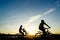 Silhouette of cyclist with child motion on sunset background