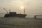 Silhouette of a cyclist passing by a ship wreak on sunset beach
