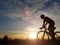 Silhouette of cyclist riding a road bike on open road in evening during sunset. Sports and outdoor activities concept