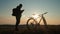 Silhouette cyclist use mobile phone on a mountain at sunset.