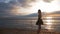 Silhouette of a dancing ballerina in black ballet tutu and pointe on embankment above ocean or sea beach at sunrise or