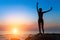 Silhouette of dancing slim woman on the ocean coast during an amazing sunset.