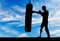 Silhouette of a disabled man with a leg prosthesis, training with a punching bag