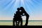 Silhouette of a disabled man in a wheelchair and his wife who is kissing by the sea