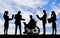 Silhouette of a disabled man in a wheelchair and his work team during a work process